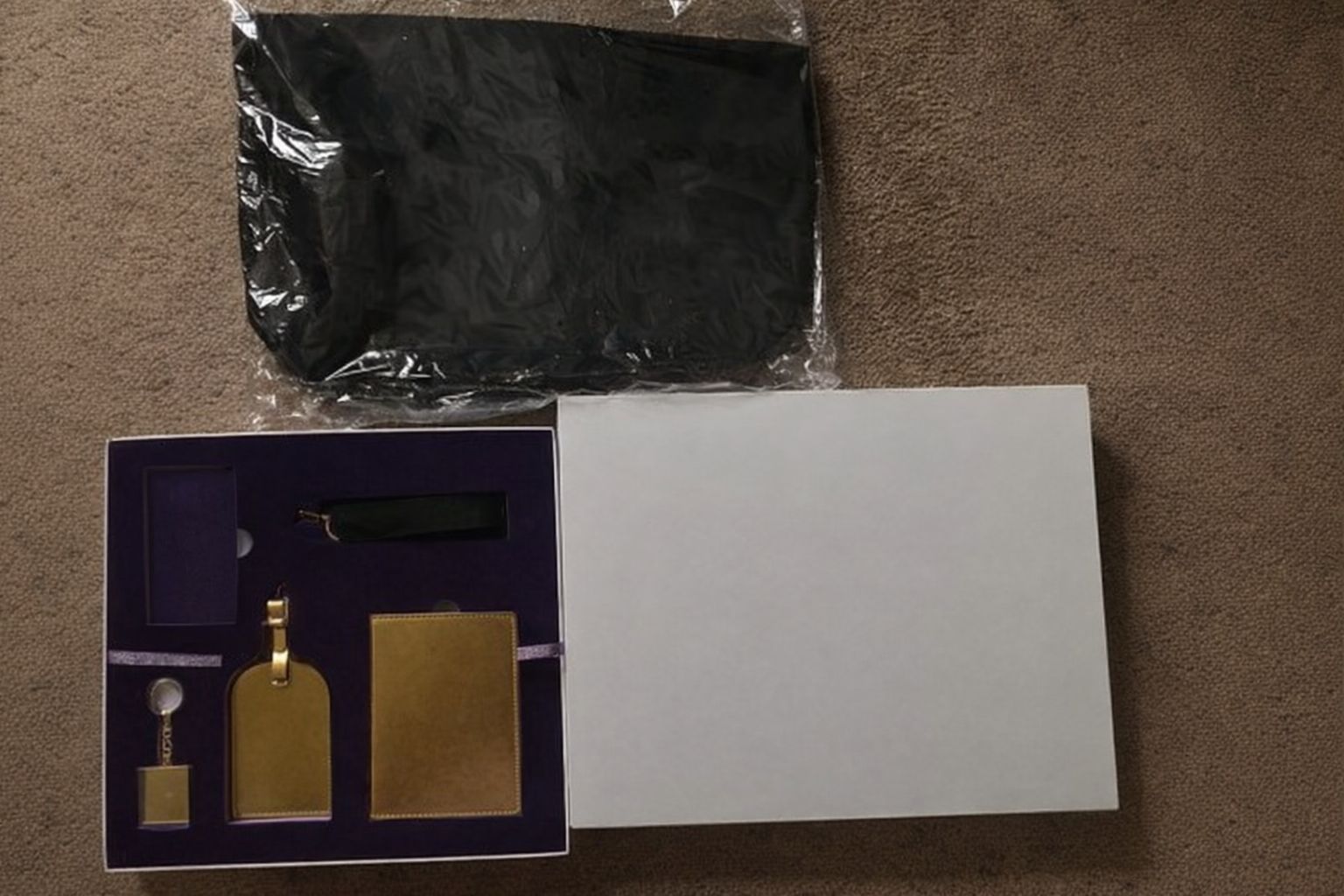 Geschenkbox mit Reiseaccessoires und schwarzem Beutel auf Teppich, relevant für Merch-Versand.