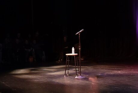 Leere Open-Mic-Bühne mit Mikrofon, Hocker und Wasserflasche im Scheinwerferlicht