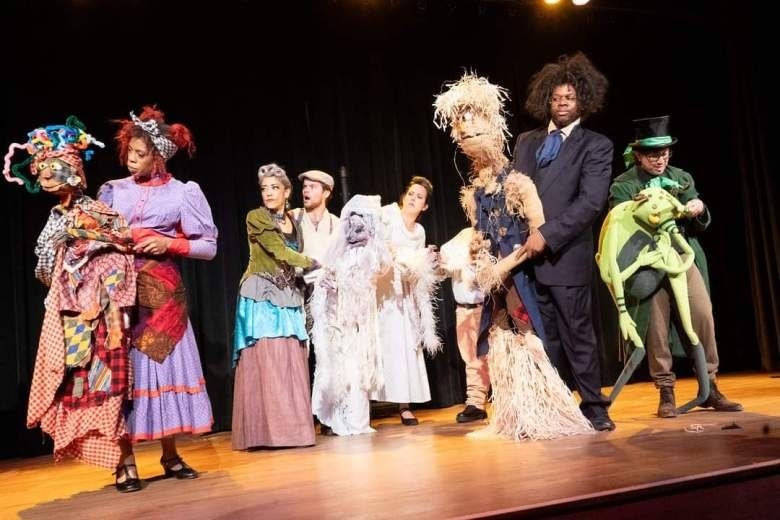 Bunt kostümierte Schauspielerinnen und Schauspieler auf einer Theaterbühne